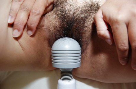 This is a big vibrator that an adult Asian brunette uses to stimulate her hairy sex area during oral sex.