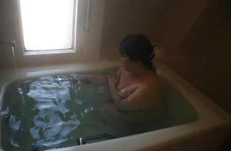 Mature brunette Eiko Imamiya takes pleasure in hot bath and displays her Asian tits.