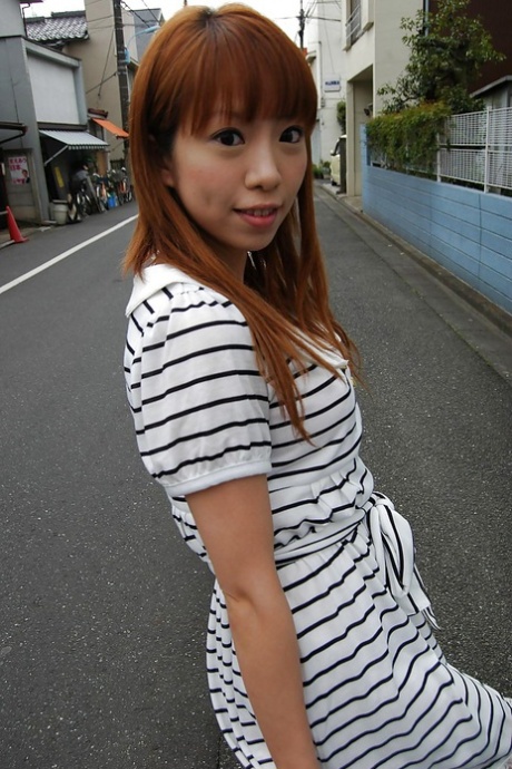 Asian Chihiro Ozawa is seen in her striped dress as she walks out the door.