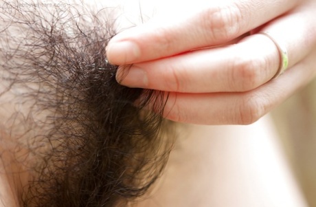 Following a slow process, an Asian woman with glasses exposes her hairy vagina in the open air.