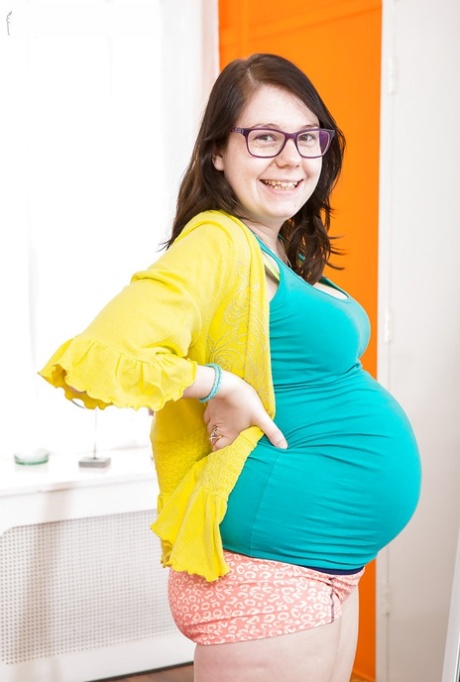 Glasses wearing amateur pregnant solo girl revealing baby bump and breasts