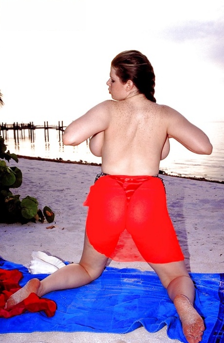 In a beach setting, Desirae, a Plump Porn star, showcases her massive saggy breast tissue.