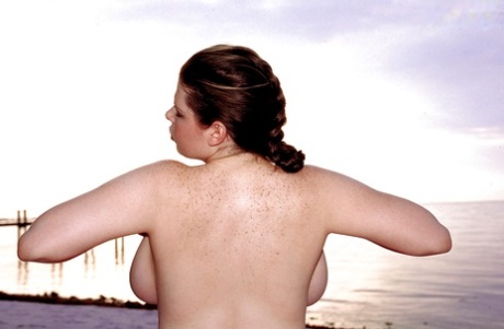 Plump porn star Desirae showcases her oversized breastbone on the beachfront.