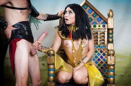 Rina Ellis, an Asian brunette, achieving a large penis while wearing a Cleopatra costume.