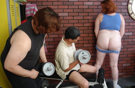 During her weight room session, Adrienne, a fat and older redhead, engages in self-pleasure by sucking and fucking two cocks.