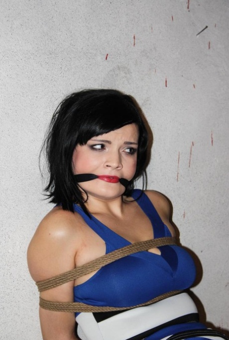 Female with dark hair is gagged and rope bound, leaving her helpless.