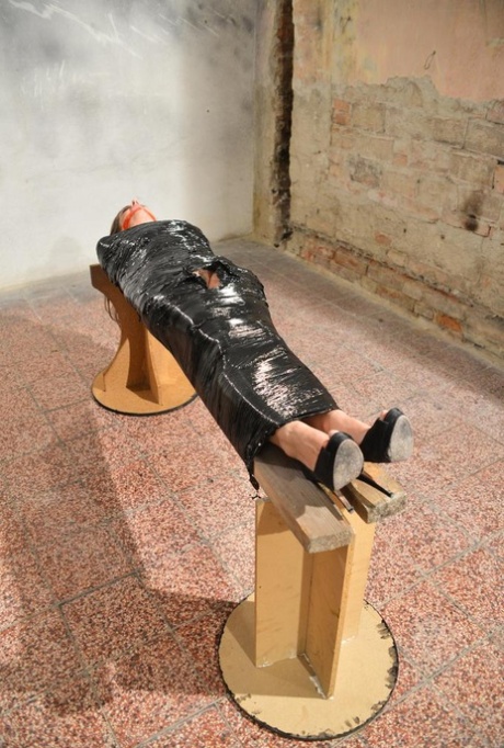 The naked female wearing high-heeled shoes is mutilated and covered in plastic, leaving her with a gagged appearance.