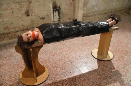 Only a naked woman wearing high-heeled shoes is petrified by plastic and looks gagged.