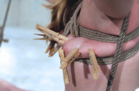Hot wax and clothespins are used to torture a female who is suspended in pain.