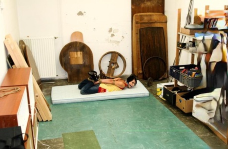 A scantily-clad woman with dark hair struggles to grip her rope bounds.