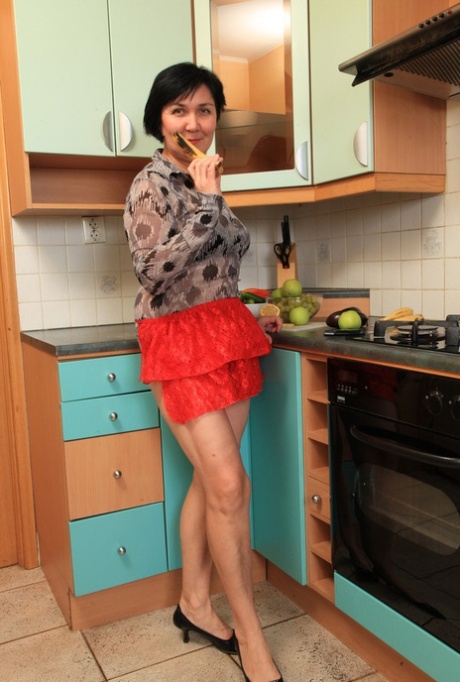 Short-haired older woman plays with her beaver while cooking something to eat.