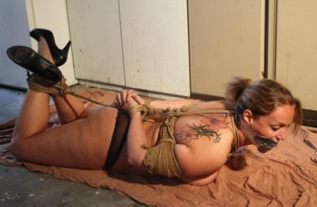 Wrapped up in blankets, a busty female is tied up with ropes and left without clothing.