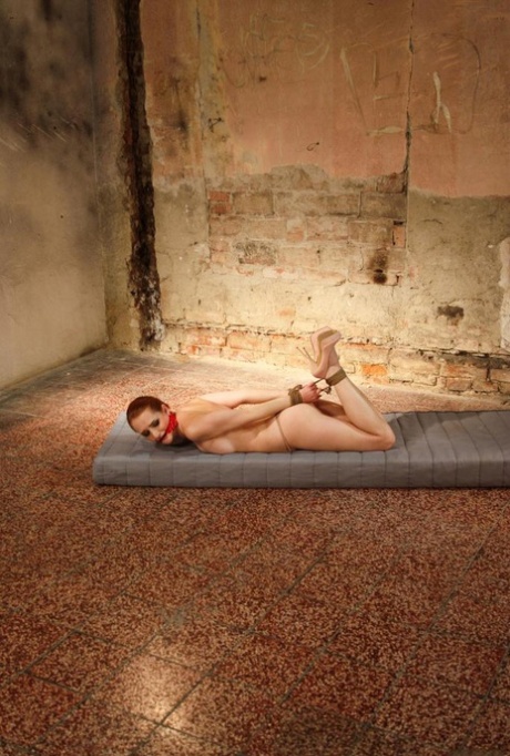 A mattress is the location where a redhead female is gagged, hogtied, and left face down.