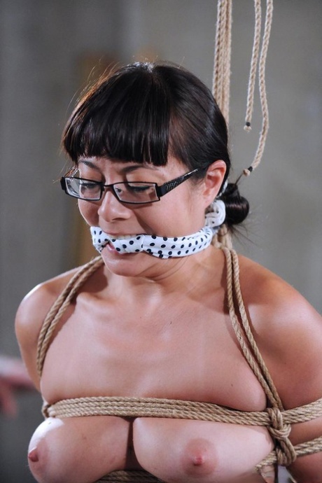 Одетая в очки азиатка подвергается насилию во время сессии шибари в бондаже