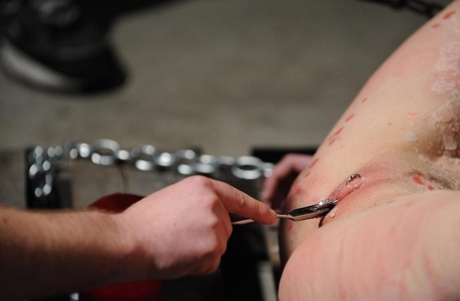 Females are chained and held in a painful BDSM session.