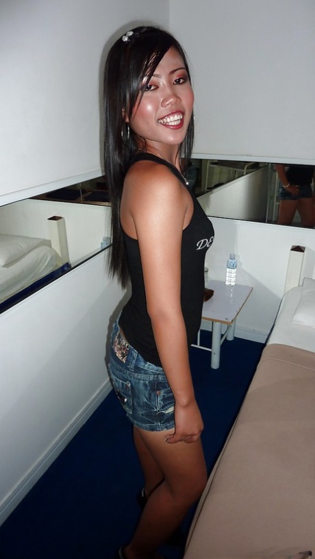 A seductive Asian female with slender legs, dressed in jeans shorts and a black top.