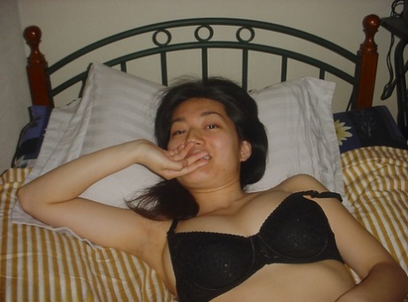 A seductive Asian babe flaunting her ample breasts while stripping off.