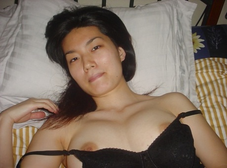 Seductive asian babe slipping off her clothes and showing off her big tits