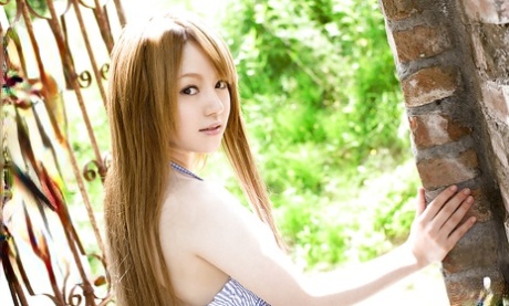 Ria Sakurai, a stunning Asian female, flaunting her graceful physique outside.