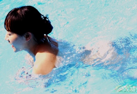 In the pool, a dashing Asian lady revels in her ample water bottles and shows off her swimsuit.