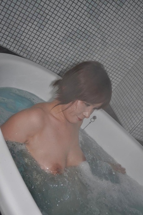 The unappealing Chiho Fujii, a skinny Asian MILF with flabby tits, taking a dip in the bathtub.