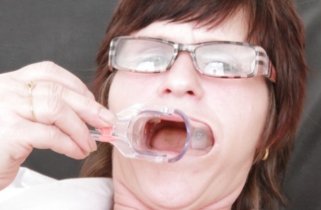 Squished nurse in glasses filling her mouth with toys and gyno equipment.