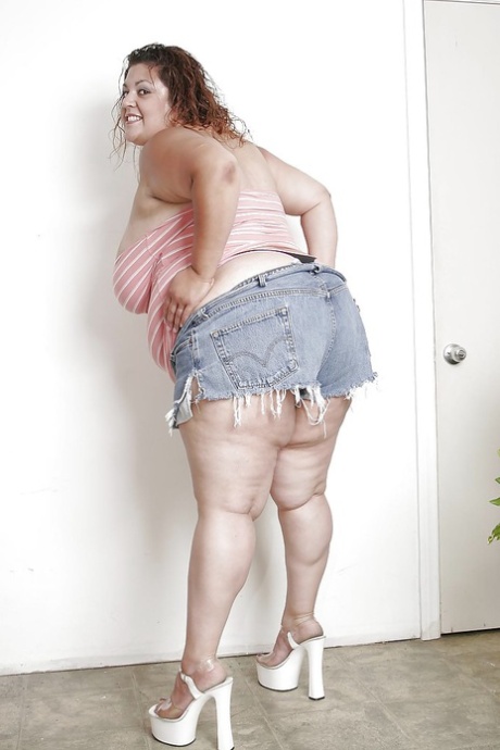 The Latina woman in jeans shorts, with an extra large size, is undressing and spreading her lips out.