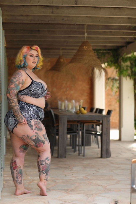Model Fatty with a tattoo, along with Galda Lou's colorful hairstyle, stripping and posing in the nude.