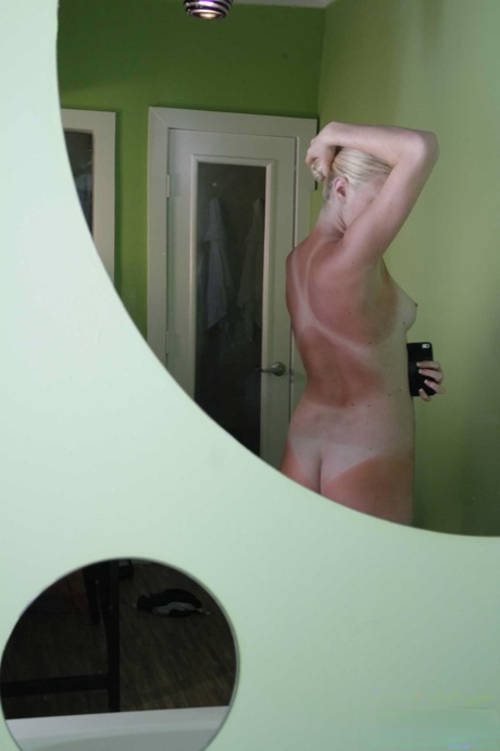 Блондинка Элли Айс делает селфи своего загорелого тела и лысой киски в зеркале