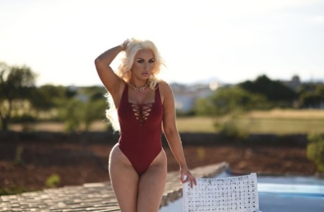 Curvy blonde babe Lucy James slowly loses her bodysuit & shows her huge tits