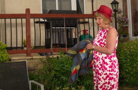 Rosemary, a British woman, plays with her bald mature pussy in the backyard.