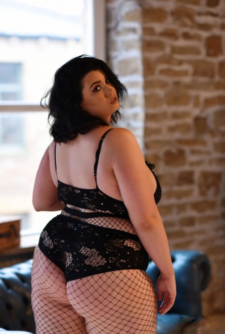 Kiki, the chubby model, removes her bra, exposes her breast tissue, and puts on fishnet tights.