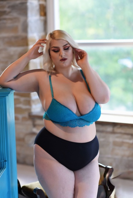 Bigger tits: Fat blonde Peaches strips off in her blue bra and shows them off.