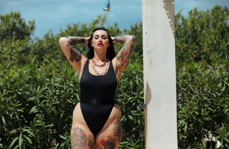 While taking a shower outside, the tattooed babe Cherrie Pie strips and wears a swimsuit.