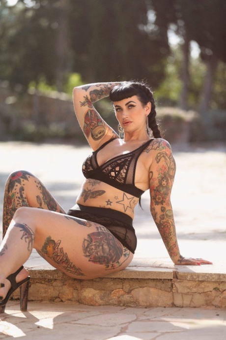 Cherrie Pie, the model with tattoos on her back and chest, displays her massive buttocks and a large bust.