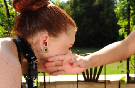 Isabel Dean is spanked by Cheryl Schroeder, who has a tattoo, while out in the sun.