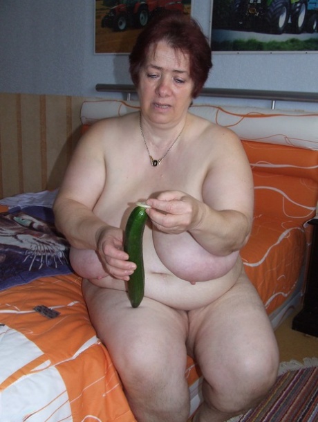 While masturbating, Corinna uses a condom and holds a large cucumber. She is also considered a fat mature woman.