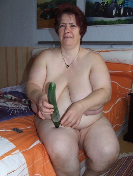 By placing a condom on an enormous cucumber and engaging in self-pleasure, Corinna, who is considered fat, mature.