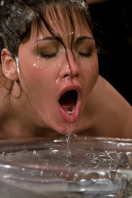 While squeezing her buttocks, Miss Jade Indica is seen with her head covered in a bucket of water.