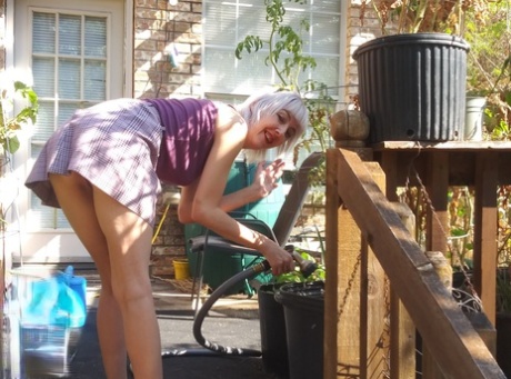 Худенькая блондинка в юбке Sylvie J светит своей киской в ​​крытом саду
