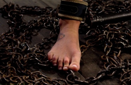 Рабыня с кляпом во рту Чарли Энн прикована наручниками к позорному столбу за порку голой БДСМ-задницы
