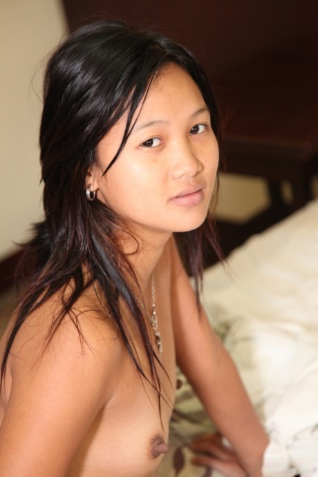 On her bed, an attractive Asian girl from Ireland offers sexy impressions with her mouth-watering puffs and petite tummies.