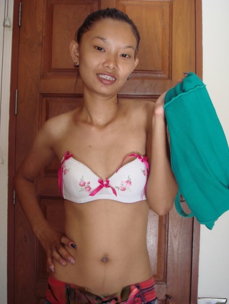 Fragile Thai girl takes her panties off and stays naked in doorway