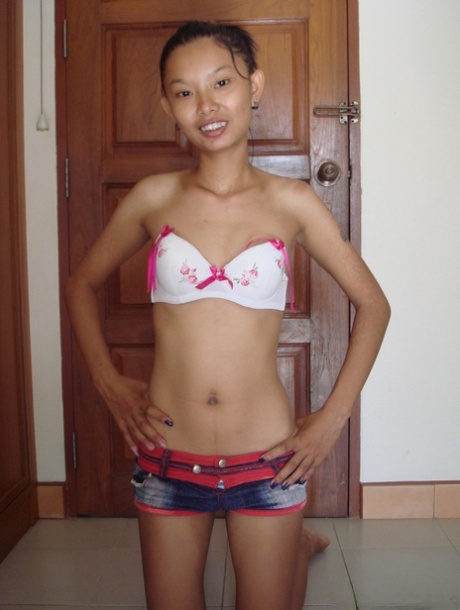 Fragile Thai girl takes her panties off and stays naked in doorway