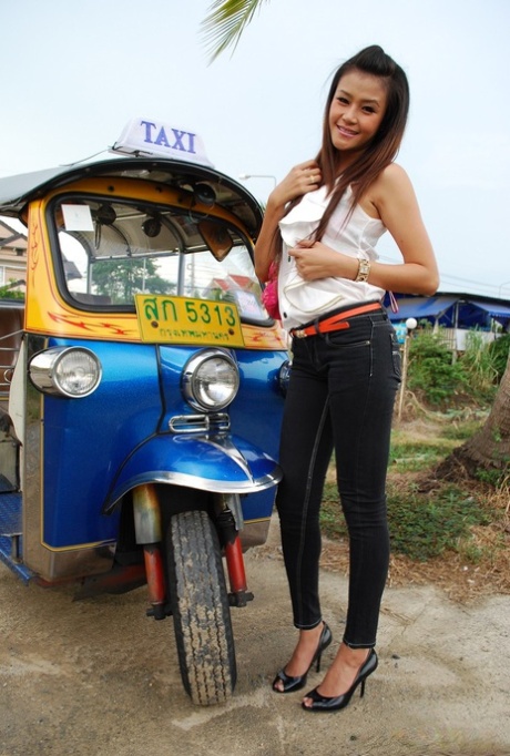 In her bra, a sweet Thai girl exposes her tight jeans while on a bed.