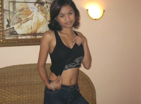 During her first nude poses, a Filipina female removes her blue jeans.