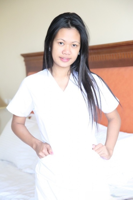 Flourishing Filipina nurses, Joanna and Joy are photographed wearing white uniforms while resting on the bed.