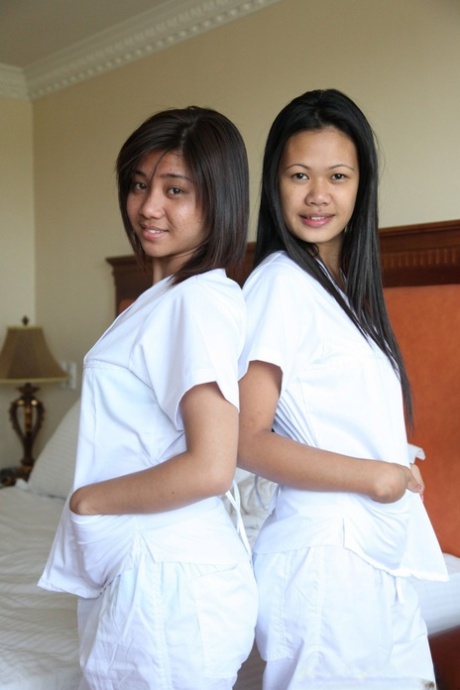 Wearing white uniforms, Joanna and Joy pose for a picture on the bed with their lively Filipino nurses.