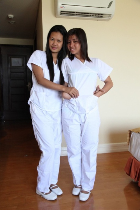 Joanna and Joy, nurses who are lusty Filipinos, stand on the bed while wearing white uniforms.