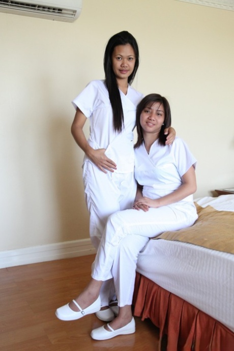 Nurses Joanna and Joy, who wear white uniforms, pose for a picture on the bed with their lively Filipino counterparts.